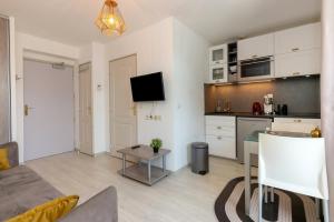 a kitchen and a living room with a couch and a table at Studio Le Splendid 3 Hôtel étoiles in Allevard