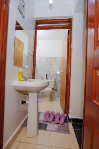 a bathroom with a sink and two pink slippers at Manta Suites Air B&Bs Thika in Thika