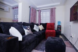 a living room with a black couch and a red stool at Manta Suites Air B&Bs Thika in Thika