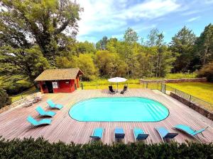 a swimming pool on a deck with chairs and an umbrella at Les bouleaux in Cussac +24 photos