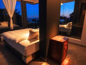 a bedroom with a bed and a large window at Teupin Layeu Hotel in Iboih