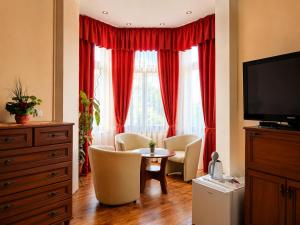 a living room with red curtains and a table and chairs at Olymp penzion in Komárno