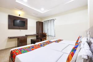 a bedroom with a bed and a desk and a television at FabHotel Anu Grand - Vijayawada in Vijayawāda +35 photos