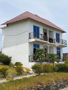 a white house with blue windows and a balcony at Nyota Apartment in Nungwi +16 photos
