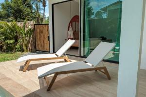 two white chairs sitting on the patio of a house at Samma Villas - Ruby Villa - 2 BDR & private pool in Ko Phangan