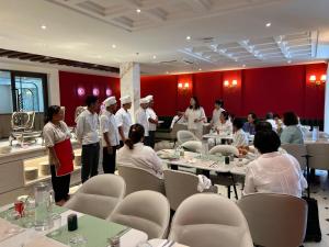 a group of people standing in a room with tables at Metta Shaanti Hotel Shravasti in Khargupur