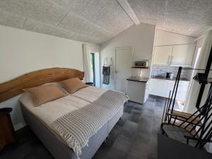 a bedroom with a large bed and a kitchen at Tiny Guesthouse in Nakskov