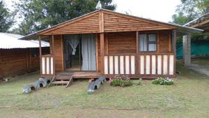 a small wooden cabin with a bench and flowers at Wanderlust Bergville in Bergville