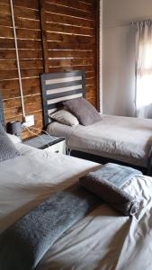 a room with three beds and a wooden wall at Wanderlust Bergville in Bergville