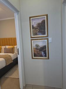 two pictures hanging on a wall next to a bed at Classy and Cosy 5 in Fourways