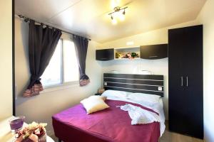 a bedroom with a large bed with a purple blanket at Bungalow Chalet sulla Spiaggia in Chioggia