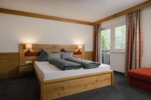 a bedroom with a bed with a wooden headboard and a window at Appartement Désirée inkl der SUPER SOMMER CARD im SOMMER 2026 in Serfaus