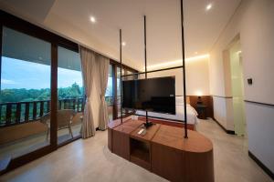 a bedroom with a large television and a balcony at Padang Padang Inn in Uluwatu