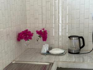 a counter with a coffee maker and flowers on it at Nyota Apartment in Nungwi