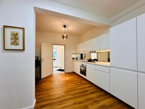 an empty kitchen with white cabinets and wood floors at White Oak Loft in Schottwien