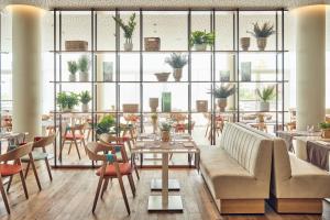 a restaurant with a couch and tables and chairs at Falkensteiner Hotel & Spa Jesolo in Lido di Jesolo