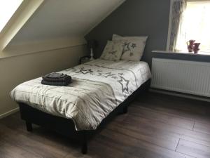a bedroom with a bed with a comforter and a window at 't Skoallehus in Steggerda