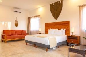 a bedroom with a large bed and a couch at Collection O Kaab Downtown Tulum in Tulum