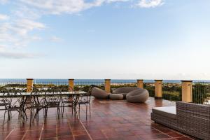 a patio with tables and chairs and a view of the ocean at Hotel Resort La Rosa Dei Venti in Portopalo