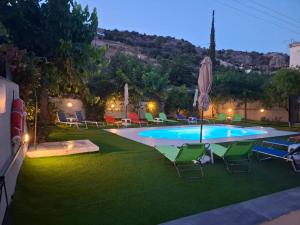 a pool with chairs and an umbrella on the grass at Vivari Acta in Vivari