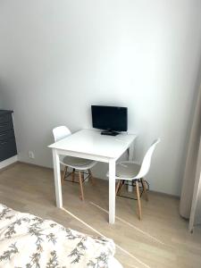 a white desk with two chairs and a computer on it at Syke Apartment Jyväskylä in Jyväskylä