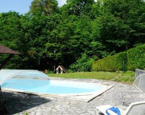 a swimming pool in a yard with chairs and trees at Gîte Le Haut-Perché, 4 personnes in Saint-Gervais-la-Forêt