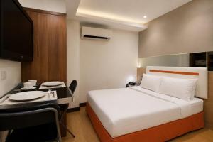 a bedroom with a bed and a desk with a television at Suk41 Bangkok Hotel in Bangkok