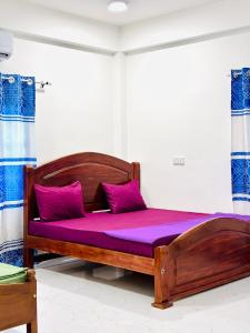 a bedroom with a wooden bed with purple sheets at Viyona Guest House in Trincomalee