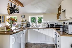 a kitchen with white cabinets and a counter top at Downclose Piggeries in North Perrott