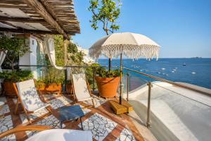 a balcony with chairs and an umbrella and the ocean at Luxury Maison Cherie - Positano Charme & Sea View in Positano