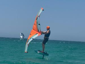 a man on a surfboard with a kite in the ocean at Sole di Sicilia in Locogrande