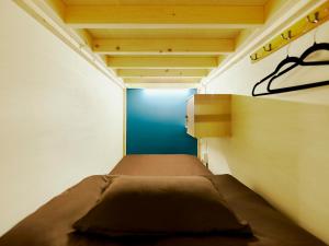 a small bedroom with a bed and a blue wall at Akasaka Guesthouse HIVE in Tokyo