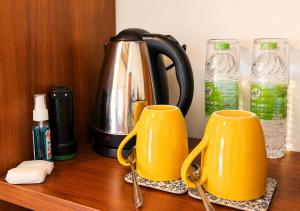 two yellow mugs on a wooden counter with water bottles at Belihuloya Escape and Cafe in Belihuloya