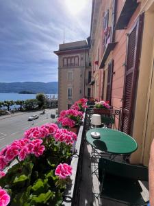 a balcony with pink flowers and a table and chairs at Casa Gambusso historical house magnificent Lake View in Verbania