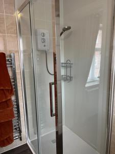 a shower with a glass door in a bathroom at Beach Front House in Walton-on-the-Naze +20 photos