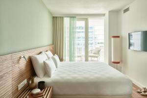a hotel room with a large white bed and a balcony at Falkensteiner Residences Jesolo in Lido di Jesolo