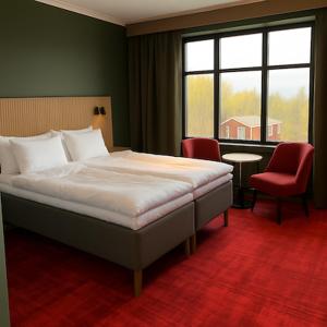 a bedroom with a bed and a chair and a window at Saxnäsgården Hotell in Saxnäs