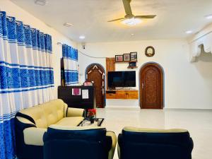 a living room with a couch and chairs and a tv at Viyona Guest House in Trincomalee