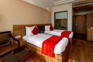 a bedroom with two beds and a chair in a room at The Grand Ambassador in Phagwāra +46 photos