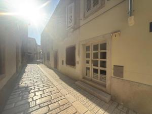 an alley with the sun shining on a building at San Mauro rooms in Poreč