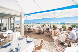 a restaurant with white tables and people sitting at tables at Hotel Le Palme - Premier Resort in Milano Marittima