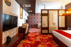 a hotel room with a bed and a tv and a bedroom at The Grand Ambassador in Phagwāra