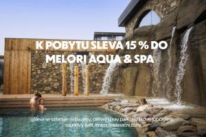 a man and woman in a swimming pool next to a waterfall at Wellness apartmány BARTH Holiday in Dolní Morava