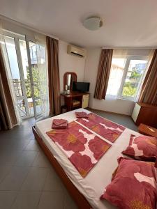 a bedroom with a bed with a flower blanket on it at Hotel Filland in Sozopol