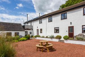 a wooden bench in front of a white building at Oakbank Farm in Lamlash