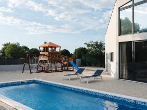 a swimming pool with a playground next to a house at Villa Bagulina in Drniš