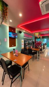 a restaurant with wooden tables and chairs and red lighting at Hotel Apsara Temerloh Gateway in Temerloh