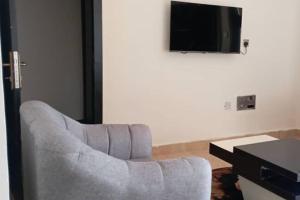 a living room with a chair and a flat screen tv at Apartment Sleeps 4 with Balcony and Parking in Asaba