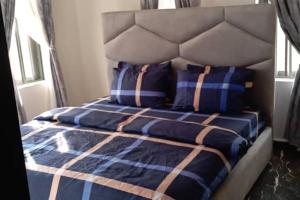 a bed with blue and white sheets and pillows at Apartment Sleeps 4 with Balcony and Parking in Asaba