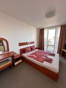 a bedroom with a bed and a desk and a window at Hotel Filland in Sozopol